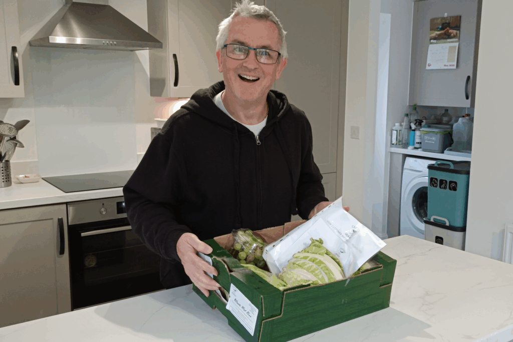 G3 holding a green cardboard local veg box from East Kent Growers