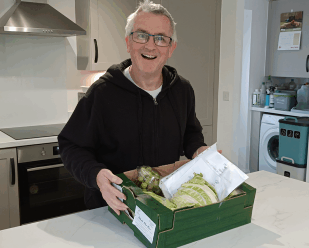 G3 holding a green cardboard local veg box from East Kent Growers