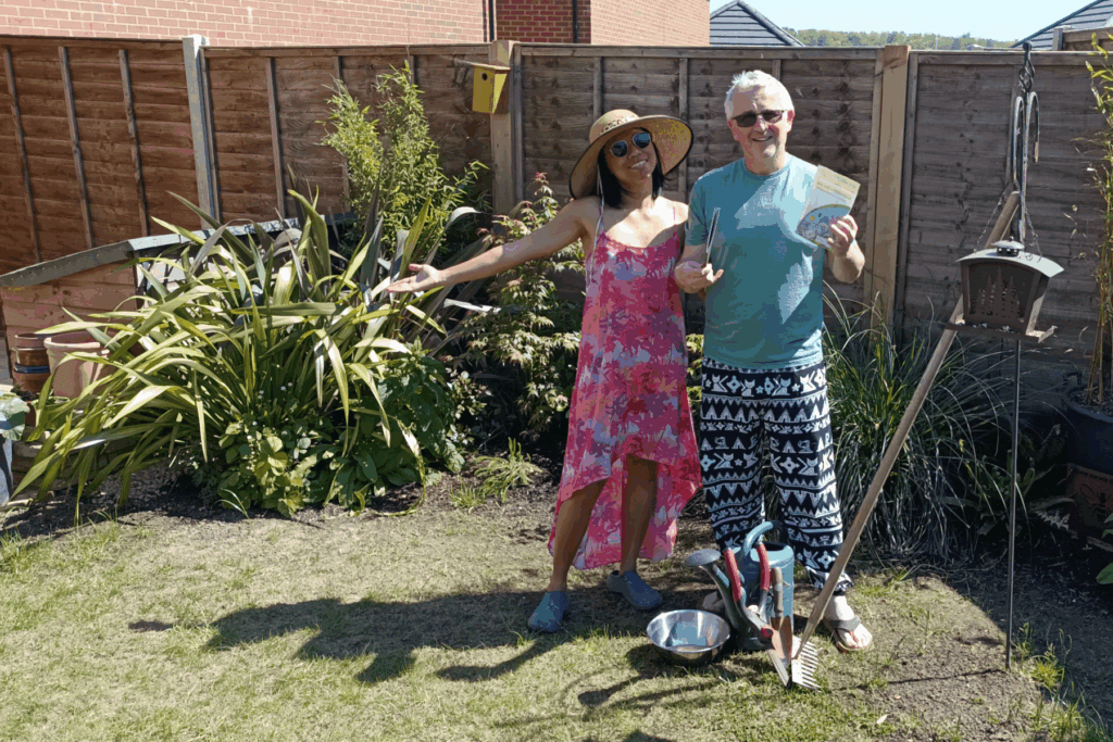 Couple standing in garden by tools and holding seeds to sow a wildflower garden