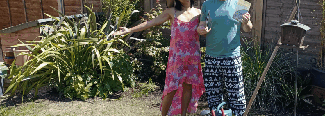 Couple standing in garden by tools and holding seeds to sow a wildflower garden